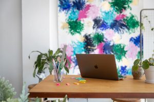 macbook on a modern wood work table in front of a modern art canvas, ways to build your business